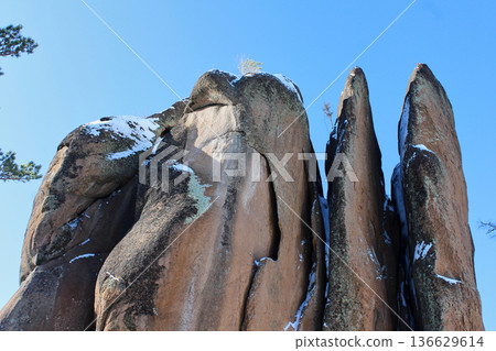 Granite rock formations covered with snow in Krasnoyarsk Stolby national park. Winter nature adventure and climbing concept. Perya rock. Granite rock formations covered with snow in Krasnoyarsk Stolby national park. Winter nature adventure and climbing concept. Perya rock. 136629614