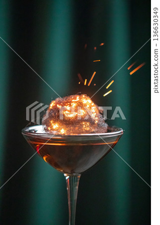 Cocktail with burning cotton candy garnish Cocktail with burning cotton candy garnish 136630349
