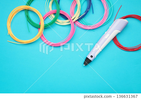 Children's 3D handle with plastic coils red, white, yellow, blue on blue background. Plastic PLA and ABS filament material for printing on a 3D pen 136631367