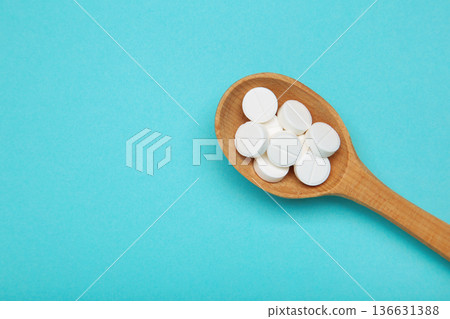 White pill's on wooden spoon on blue background. Top view White pill's on wooden spoon on blue background. Top view 136631388