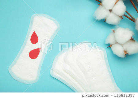 Sanitary pad with cotton flower on blue background. Daily feminine hygiene product. Sanitary pad with cotton flower on blue background. Daily feminine hygiene product. 136631395