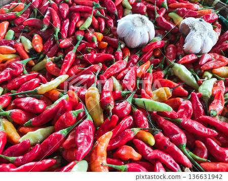 Vibrant Red Chili Peppers and Garlic Piled in a Basket at a Traditional Market 136631942