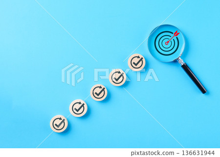 Business target and goal achievement steps concept. Wooden blocks check marks and magnifying glass on target symbolizing success, progress, growth, task completion, performance optimization strategy, Business target and goal achievement steps concept. Wooden blocks check marks and magnifying glass on target symbolizing success, progress, growth, task completion, performance optimization strategy, 136631944