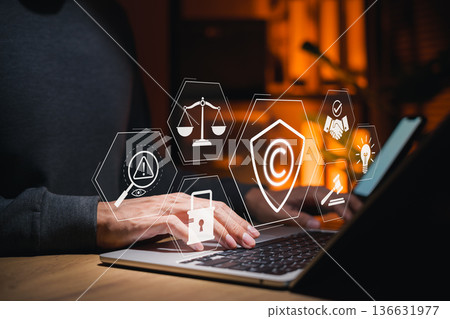 Businessman using laptop with copyright protection and intellectual property icons, represent digital rights management, online security, legal ownership, content regulation, copyright law enforcement 136631977