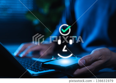 Facial recognition and Face ID biometric authentication concept. User holding smartphone, face scan icon, and check mark, representing cybersecurity, digital identity and secure mobile access. Facial recognition and Face ID biometric authentication concept. User holding smartphone, face scan icon, and check mark, representing cybersecurity, digital identity and secure mobile access. 136631979