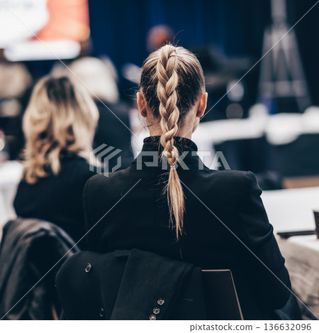 Rear view of a unrecognizable business woman wearing beautiful hair bun attending conference business meeting Rear view of a unrecognizable business woman wearing beautiful hair bun attending conference business meeting 136632096