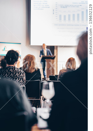 Speaker giving a talk in conference hall at business event. Rear view of unrecognizable people in audience at the conference hall. Business and entrepreneurship concept Speaker giving a talk in conference hall at business event. Rear view of unrecognizable people in audience at the conference hall. Business and entrepreneurship concept 136632129