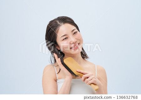 Young woman combing her hair with a brush Young woman combing her hair with a brush 136632768