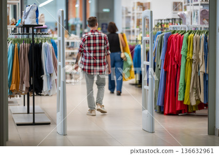 Customers walking through a clothing store entrance between security gates Customers walking through a clothing store entrance between security gates 136632961