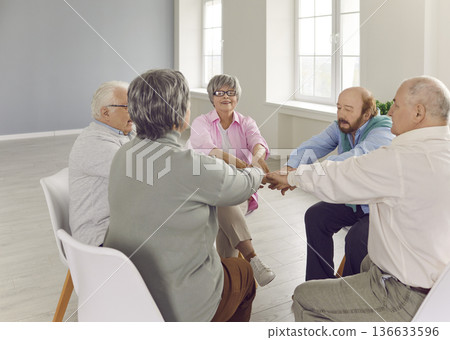 Senior people talking on therapy session at nursing home holding hands together. Senior people talking on therapy session at nursing home holding hands together. 136633596