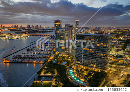 Twilight over Miami skyline and marina. Luxury yachts glowing in the Miami harbor. Sunset cruise near Miami downtown skyscrapers. Aerial night view of Miami Beach at dusk. Twilight over Miami skyline and marina. Luxury yachts glowing in the Miami harbor. Sunset cruise near Miami downtown skyscrapers. Aerial night view of Miami Beach at dusk. 136633622