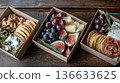 Exquisite boxes with meat snacks, cheese, nuts and fruits. Exquisite snack boxes are filled with delicacies. 136633625