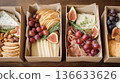 Exquisite boxes with meat snacks, cheese, nuts and fruits. Exquisite snack boxes are filled with delicacies. 136633626
