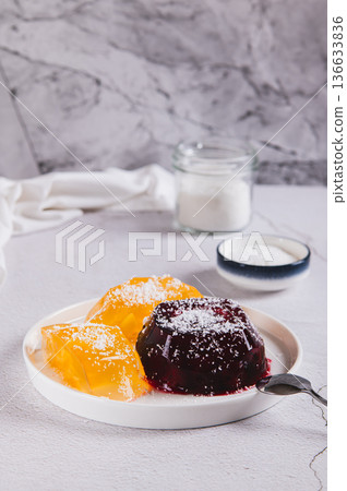Sweet fruit jelly in coconut flakes on a plate on the table vertical view Sweet fruit jelly in coconut flakes on a plate on the table vertical view 136633836