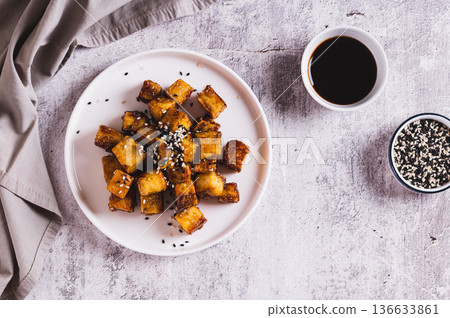 Fried tofu in soy sauce and sesame seeds on a plate on the table top view Fried tofu in soy sauce and sesame seeds on a plate on the table top view 136633861