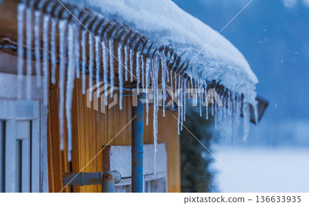 Icicles on the roof of the house. Danger of falling 136633935