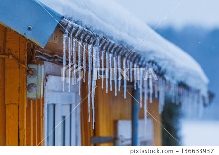 Icicles on the roof of the house. Danger of falling Icicles on the roof of the house. Danger of falling 136633937