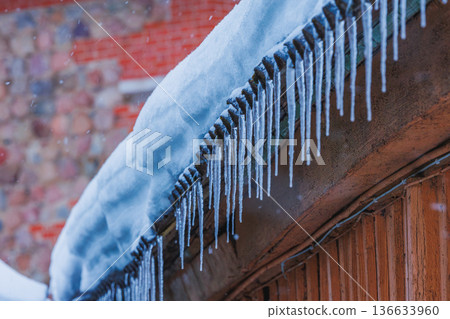 Icicles on the roof of the house. Danger of falling 136633960