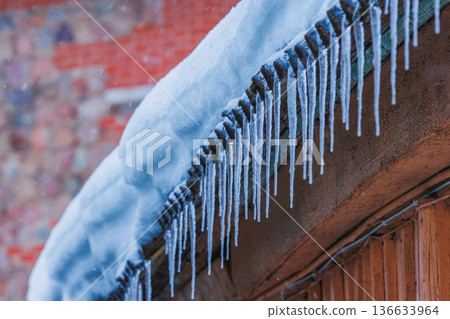 Icicles on the roof of the house. Danger of falling Icicles on the roof of the house. Danger of falling 136633964