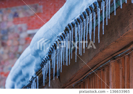 Icicles on the roof of the house. Danger of falling 136633965