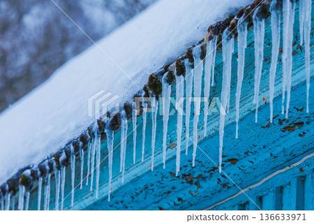 Icicles on the roof of the house. Danger of falling Icicles on the roof of the house. Danger of falling 136633971