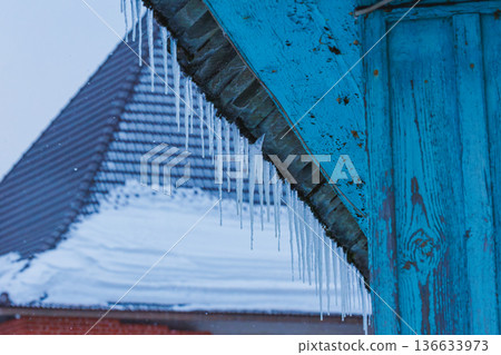 Icicles on the roof of the house. Danger of falling 136633973