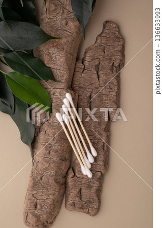 Wood cotton swabs on natural bark, green leaves Wood cotton swabs on natural bark, green leaves 136633993