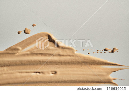 Beige liquid foundation cosmetic swatch showing creamy texture on light background 136634015