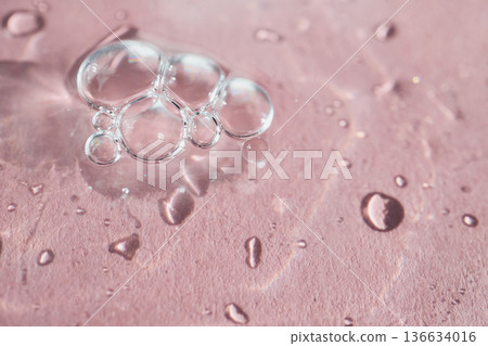 Clear bubbles and water drops creating organic patterns on pink surface 136634016