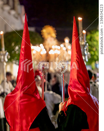 Back view of two nazarenos in red hoods with silver scepters Back view of two nazarenos in red hoods with silver scepters 136634223