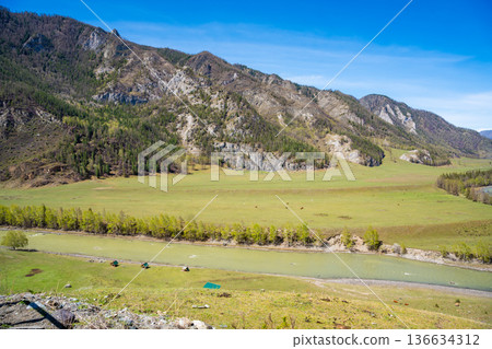 Aerial view of Chuya River flowing between mountains in Chuysky Trakt area Altai Russia. Scenic Siberian river valley surrounded by rugged terrain. Aerial view of Chuya River flowing between mountains in Chuysky Trakt area Altai Russia. Scenic Siberian river valley surrounded by rugged terrain. 136634312