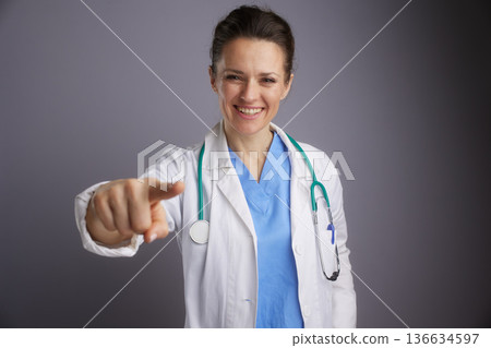Smiling Female Doctor Pointing at Camera 136634597