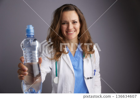 Smiling Female Doctor Offering Water for Hydration 136634607