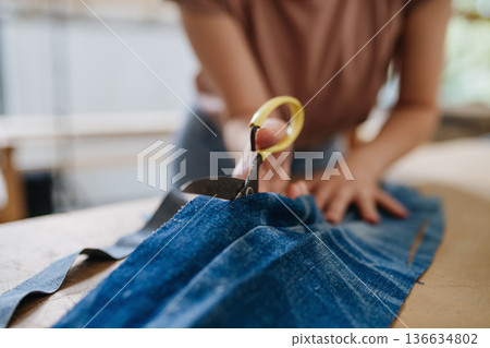Close up of person working on workbench, preparing old fabric for weaving. 136634802