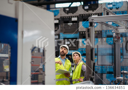 Industrial team analyzing data in high tech manufacturing plant. 136634851