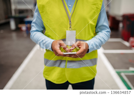 Close-up of female hands in factory using smartphone. Copy space. Close-up of female hands in factory using smartphone. Copy space. 136634857