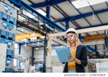 Female engineer or technician working in modern factory. Female engineer or technician working in modern factory. 136634864