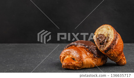 Chocolate filled croissant cut open on dark stone background Chocolate filled croissant cut open on dark stone background 136635717