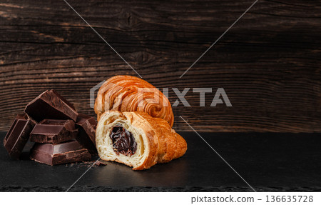 Chocolate filled croissant with dark chocolate pieces on rustic wooden background 136635728