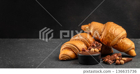 Fresh butter croissants with chocolate cream and hazelnut on dark background Fresh butter croissants with chocolate cream and hazelnut on dark background 136635736