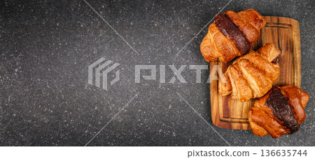 Assorted chocolate croissants on wooden board dark banner Assorted chocolate croissants on wooden board dark banner 136635744