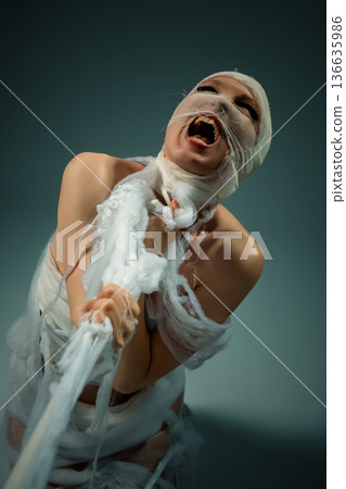 Person wrapped in white bandages screaming in anguish and struggling to break free. 136635986