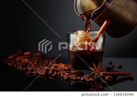 Coffee is poured into a glass with ice. Coffee is poured into a glass with ice. 136636046