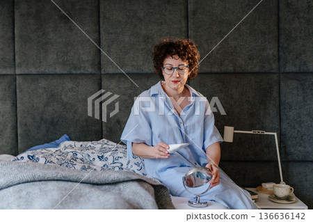 A woman in a blue armchair relaxes at home, reading a book and stroking her white cat. Concept of animal companionship, domestic peace, mindfulness, and slow living during a quiet weekend. A woman in a blue armchair relaxes at home, reading a book and stroking her white cat. Concept of animal companionship, domestic peace, mindfulness, and slow living during a quiet weekend. 136636142