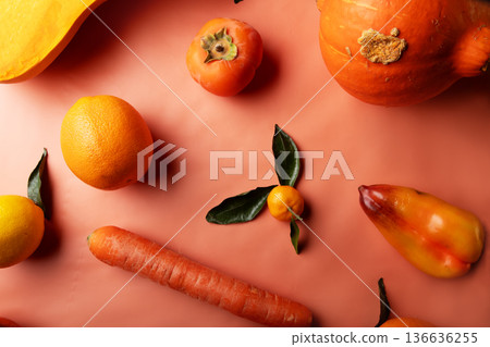 Ripe and tasty orange and yellow fruits, carrots and pumpkin around coral color background. flat lay Ripe and tasty orange and yellow fruits, carrots and pumpkin around coral color background. flat lay 136636255