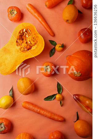 Ripe and tasty orange and yellow fruits, carrots and pumpkin around coral color background. flat lay Ripe and tasty orange and yellow fruits, carrots and pumpkin around coral color background. flat lay 136636256