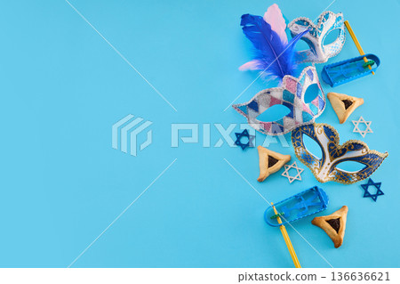 Purim holiday masks, hamantaschen, and gragger on blue background 136636621