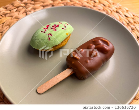 Two desserts on a plate: chocolate popsicle and green cake. Modern presentation of sweets. Food, pleasure, gastronomy concept Two desserts on a plate: chocolate popsicle and green cake. Modern presentation of sweets. Food, pleasure, gastronomy concept 136636720