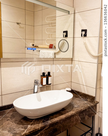 Close-up of bathroom sink with marble countertop. Cleanliness, hygiene, and modern hospitality in travel accommodation. Close-up of bathroom sink with marble countertop. Cleanliness, hygiene, and modern hospitality in travel accommodation. 136636842