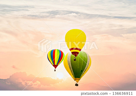 Colorful hot air balloon flying under orange sunset sky Colorful hot air balloon flying under orange sunset sky 136636911
